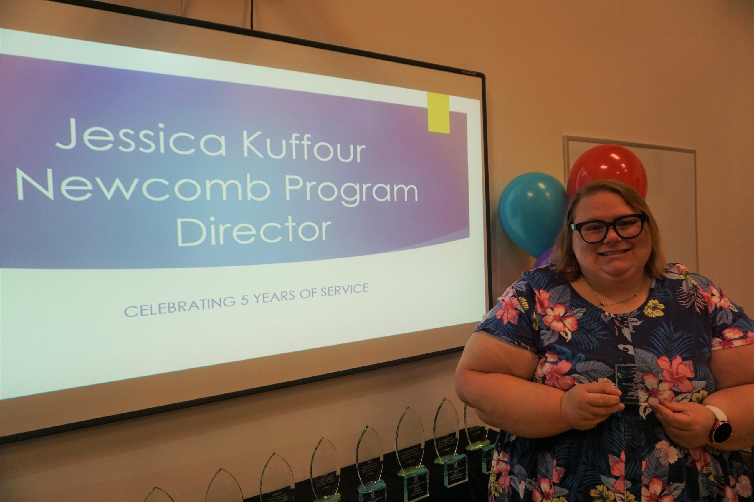 Woman stands with award in front of a screen