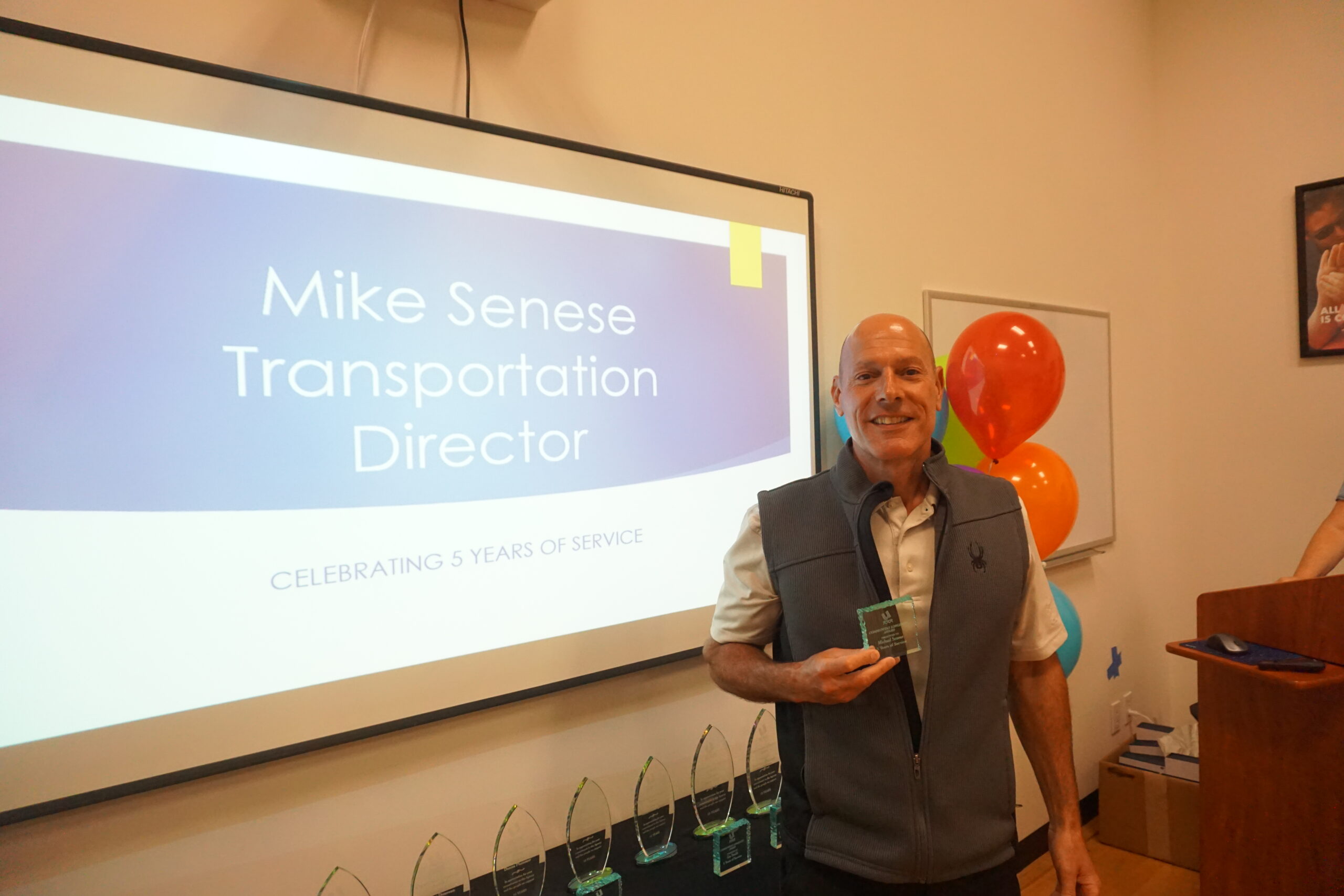 Man stands with award in front of a screen